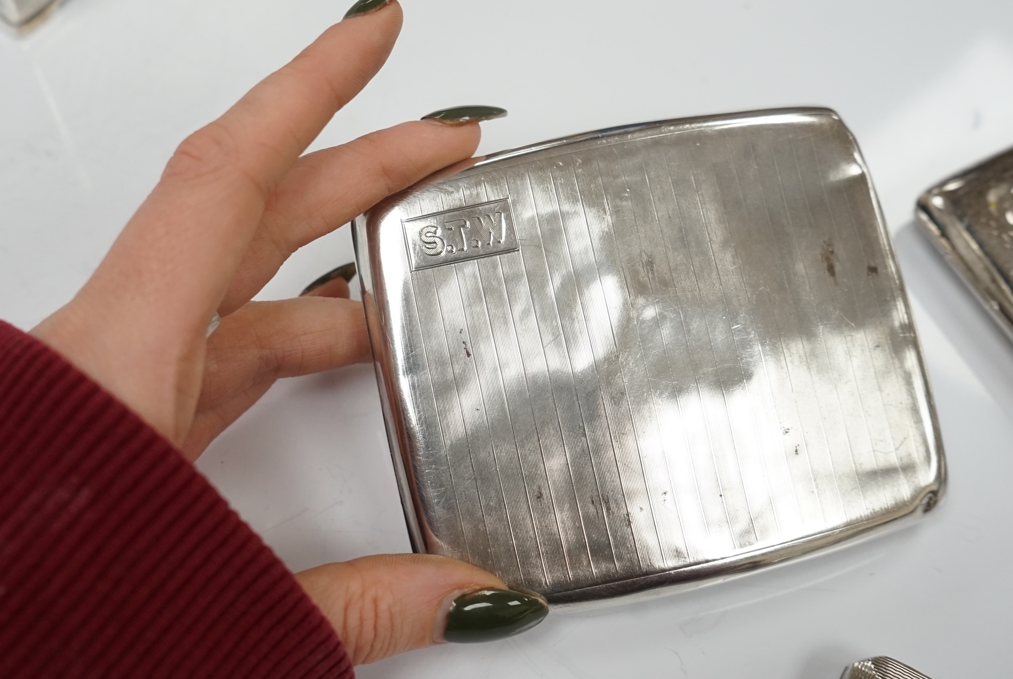 Two silver cigarette cases, a silver plated cigarette case and a Thai? white metal cigarette box, 11.6cm. Condition - poor to fair